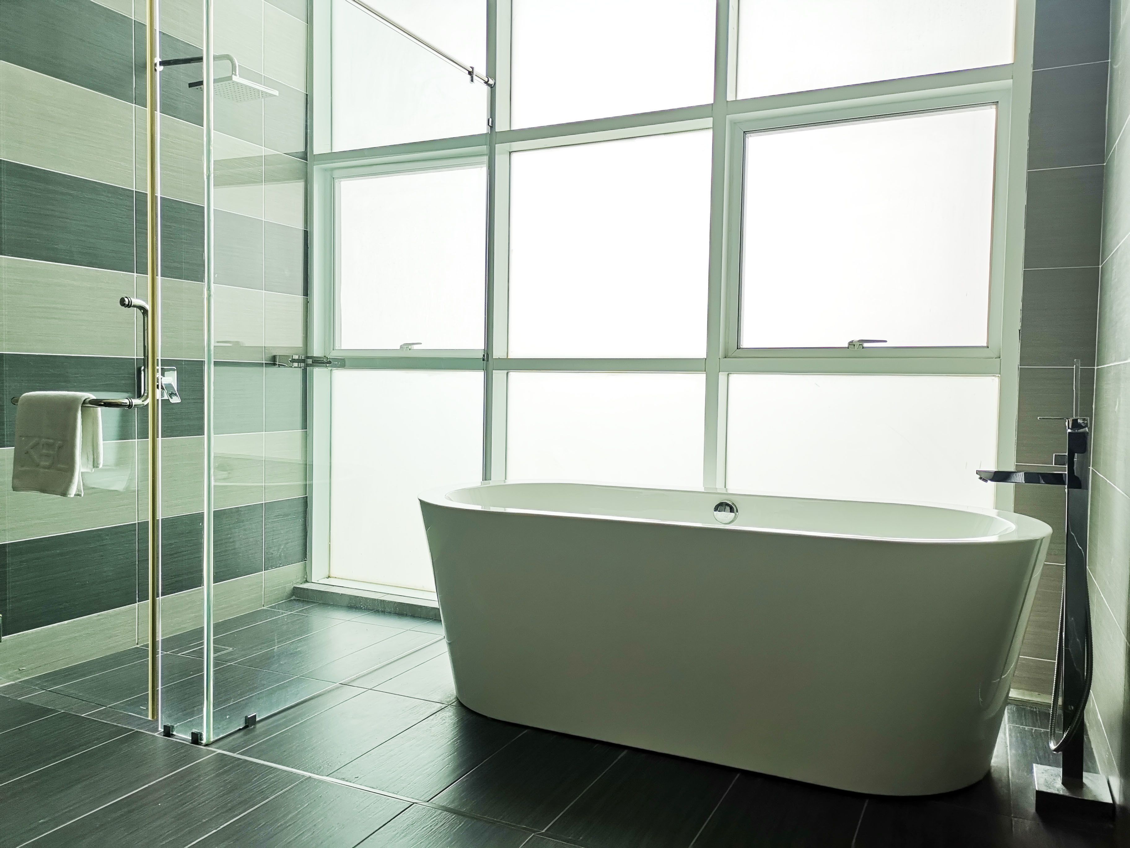 A modern bathroom with a freestanding bathtub, a glass shower enclosure, and a large window providing natural light.