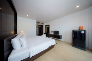 Una habitación de hotel moderna con una cama grande, un televisor de pantalla plana, un mini bar y un armario.