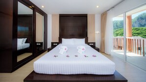 Una habitación de hotel con una cama grande, vistas a un paisaje montañoso y un balcón con barandilla.