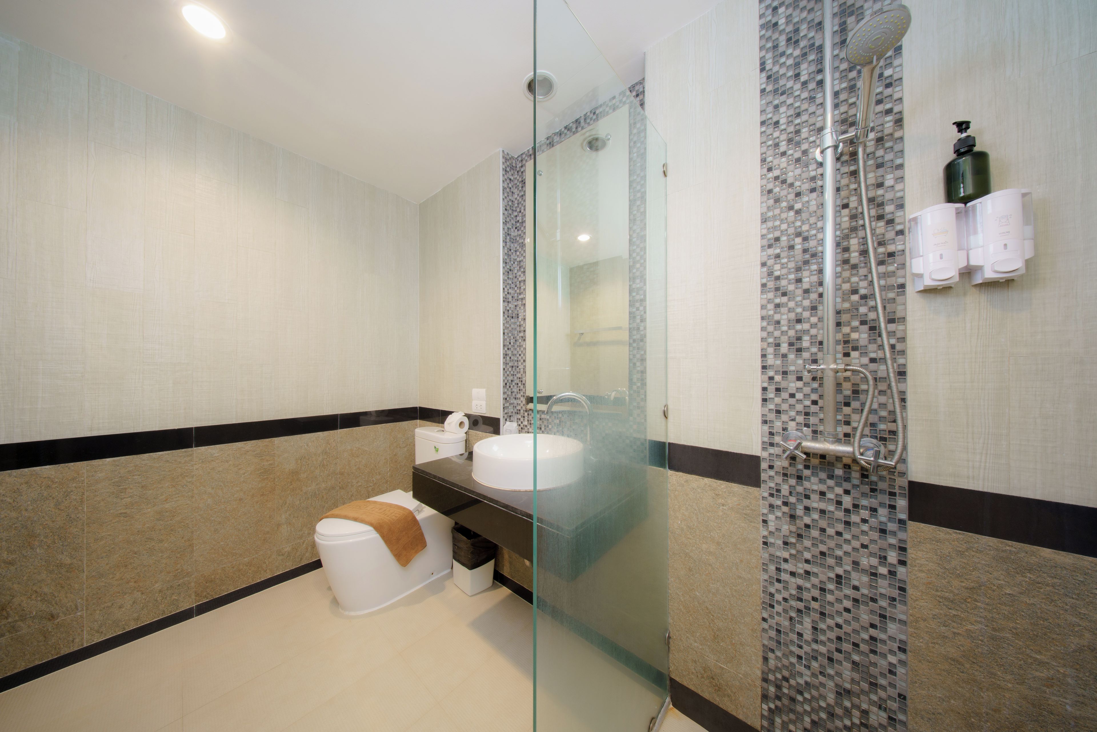 Een moderne badkamer met een glazen douchecabine, een witte wastafel en een toilet.
