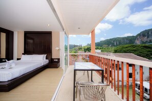 A balcony with a bed and a table, overlooking a mountainous landscape. - Aonang Regent (Krabi)