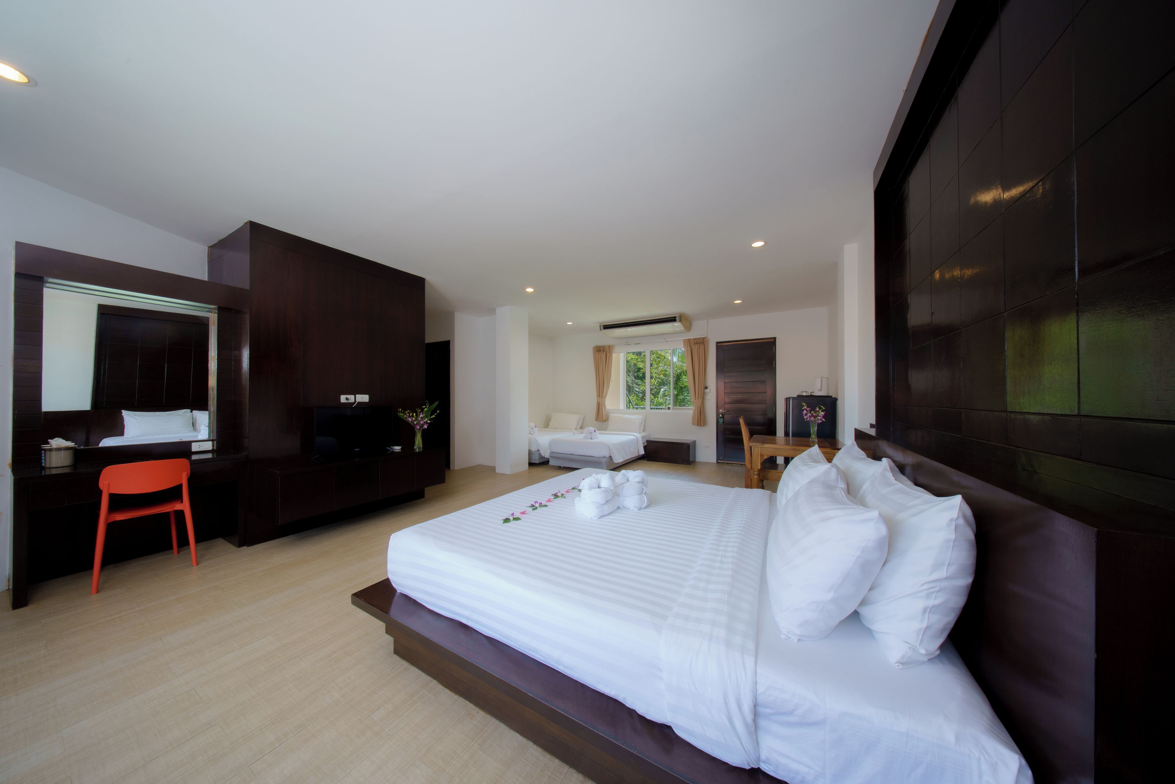 Una habitación de hotel moderna con una cama grande, un escritorio, una silla, un televisor y una ventana con cortinas.