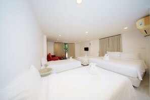 A hotel room with two single beds, a red sofa, a small table with a vase, and a television on the wall. - Aonang Regent (Krabi)