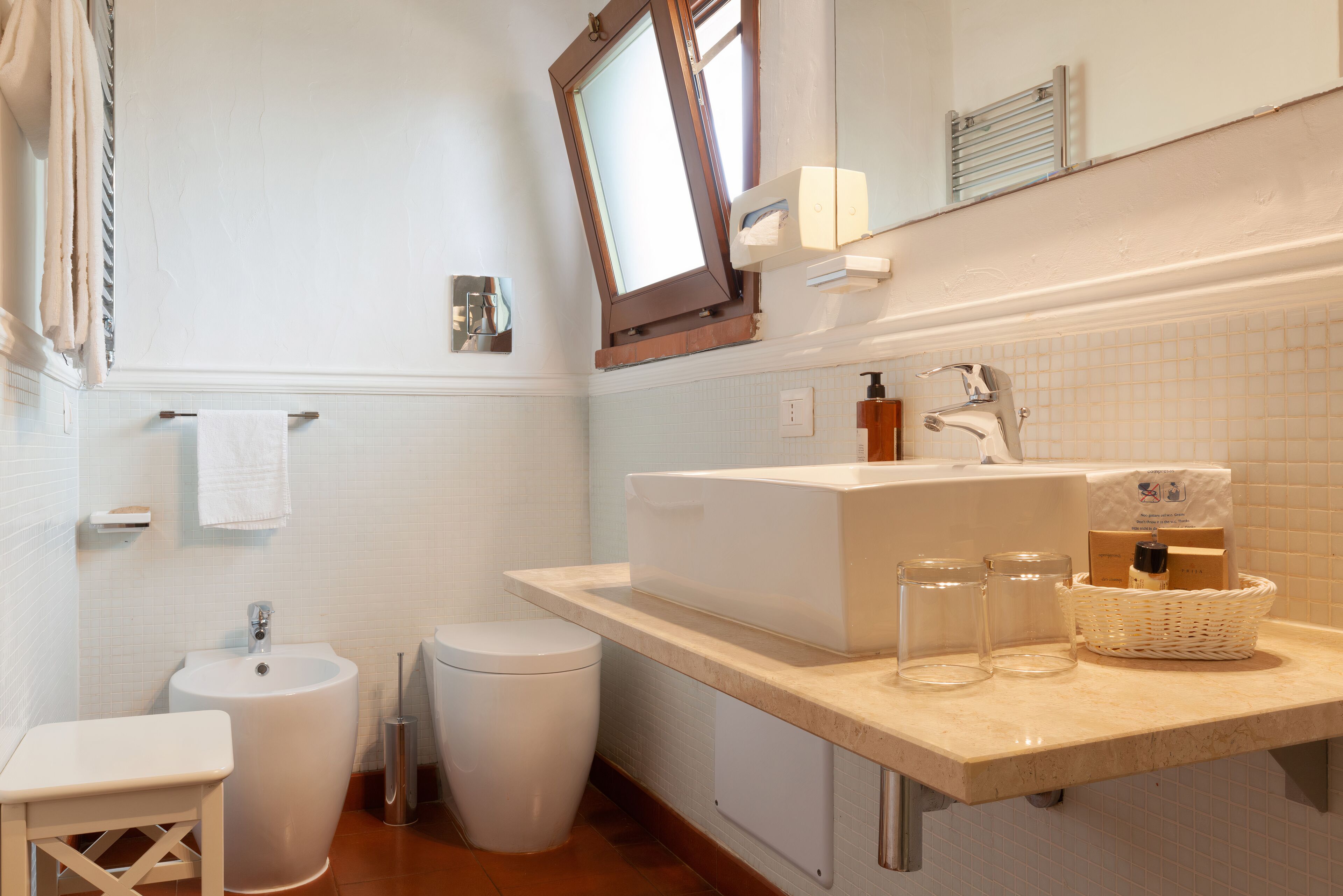 A bathroom with a sink, bidet, and a small table.