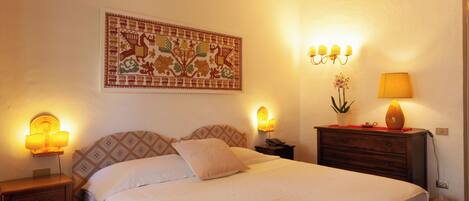 Un lit bien fait, avec une tête de lit à motifs, une tapisserie accrochée au mur et des lampes de chevet.