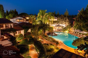 A resort with a large swimming pool, multiple lounge areas, and well-maintained gardens.