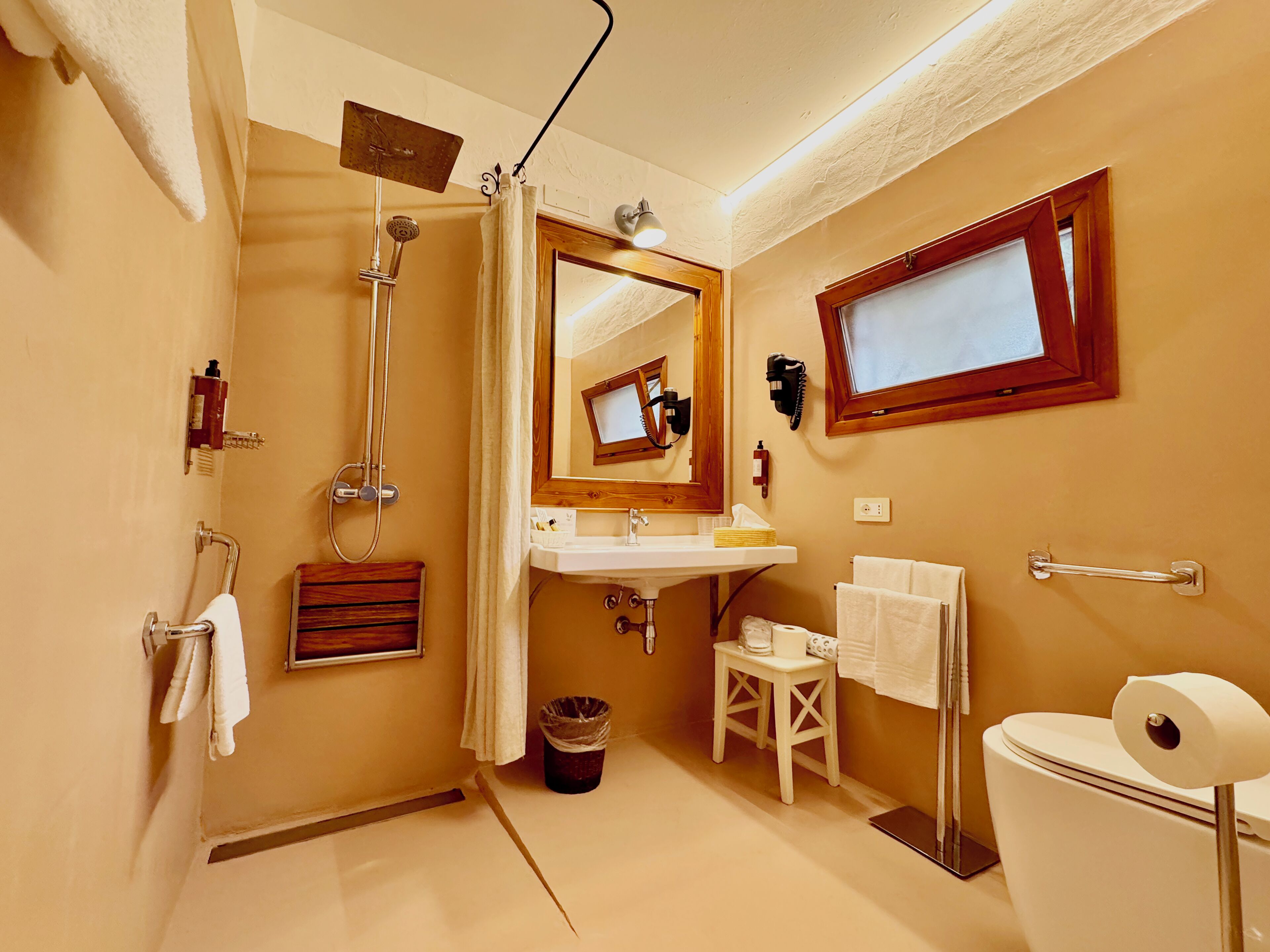 A bathroom with a shower, toilet, sink, and a mirror.