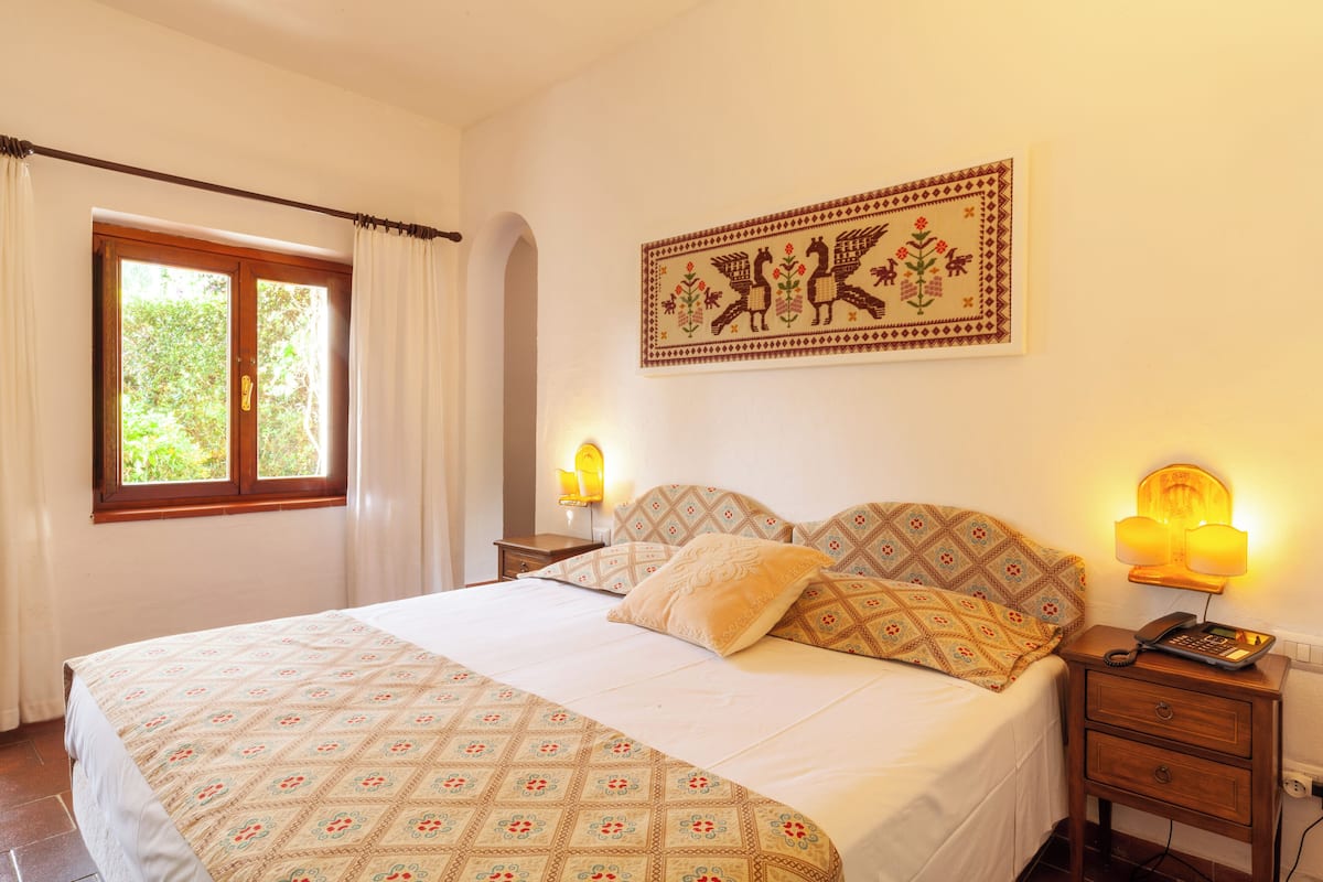 Une chambre à coucher avec un grand lit, deux lampes de chevet, une table de chevet et une tapisserie murale.
