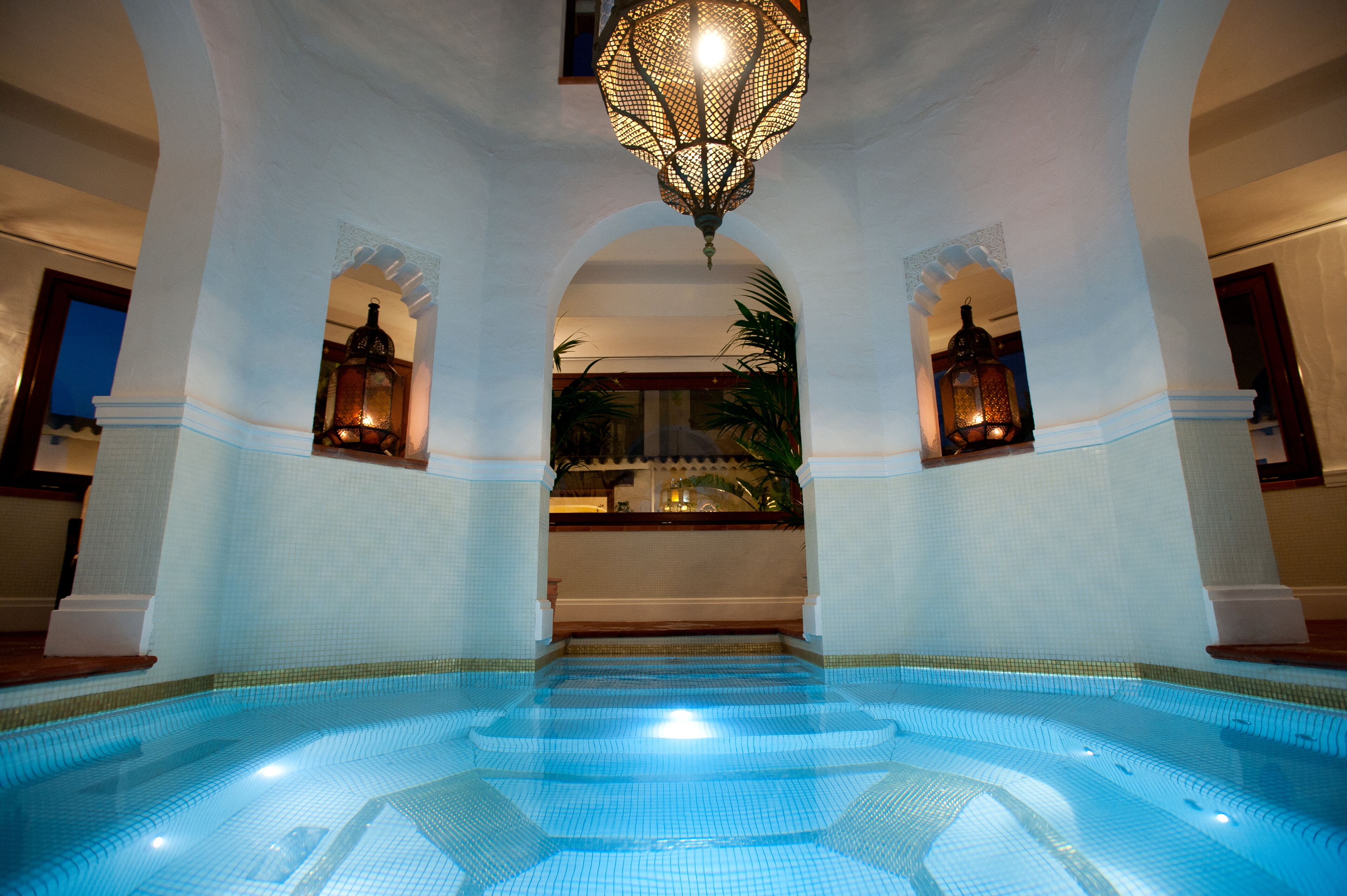 An indoor swimming pool with tiled walls and a central fountain.