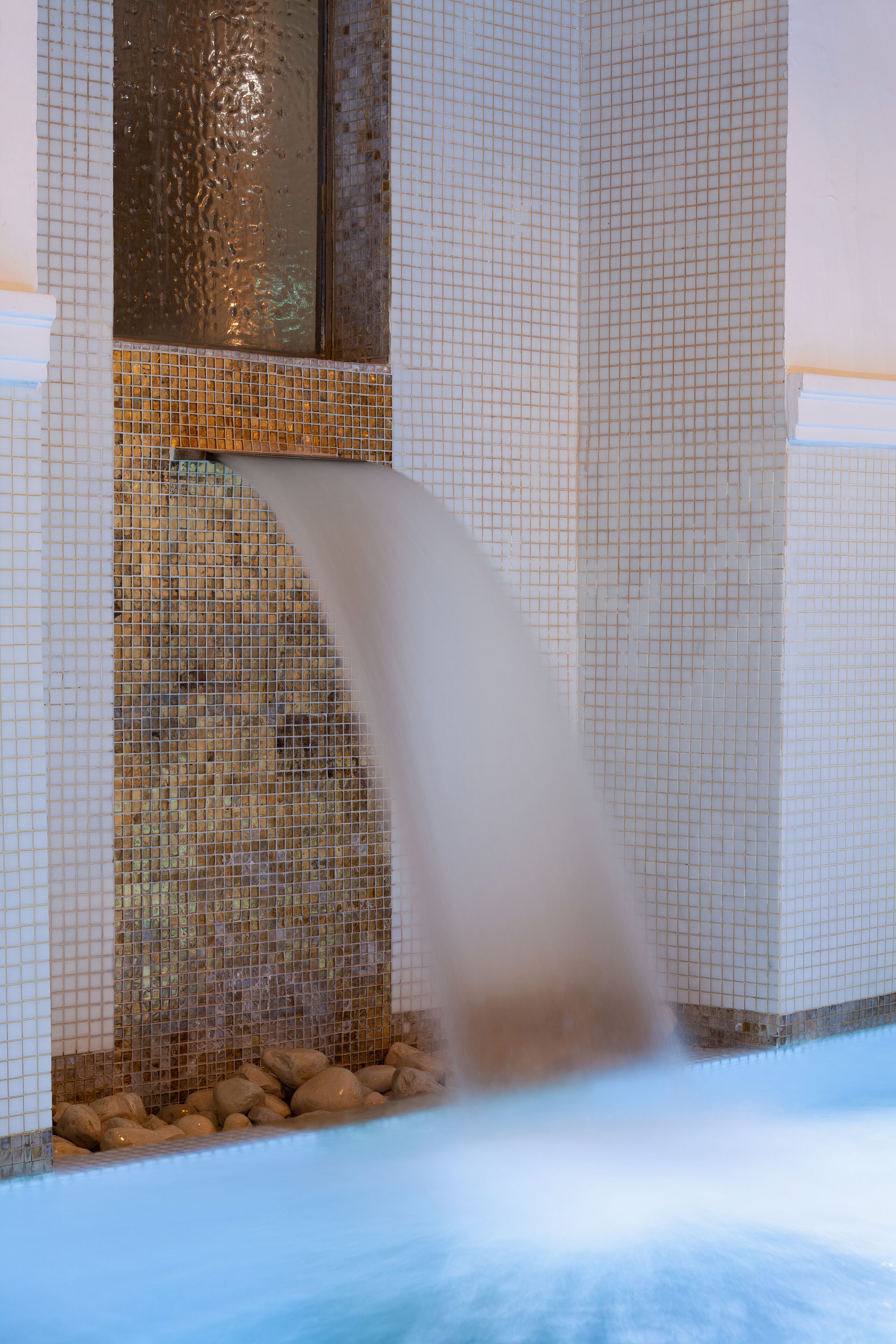 A water feature with a cascading flow, a tiled wall, and a window.