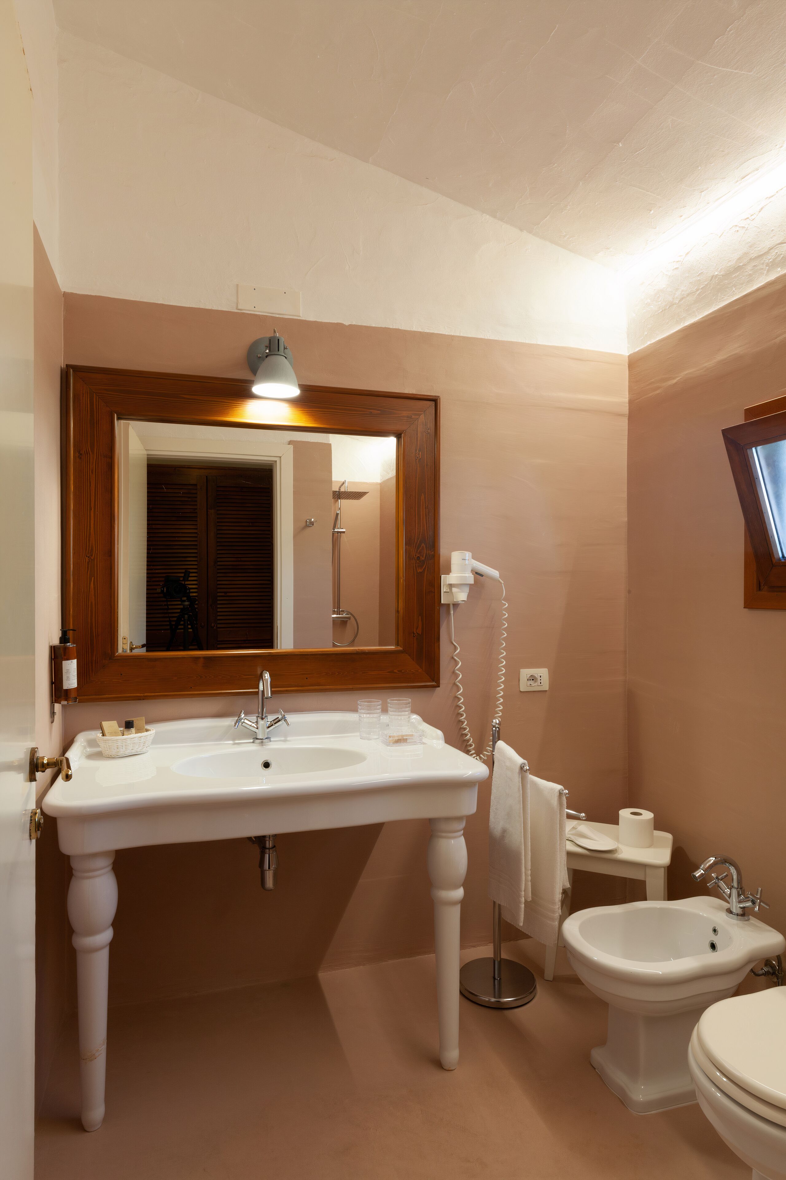 A bathroom with a white sink, a mirror, a bidet, and a toilet.