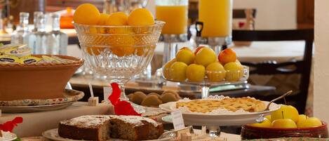 A breakfast buffet with various pastries, fruits, and beverages.