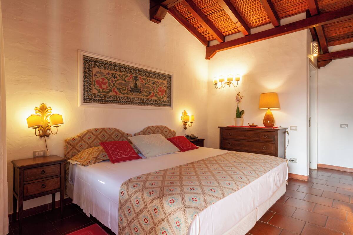 Une chambre à coucher avec un grand lit, deux tables de chevet, une commode et une lampe fixée au mur.