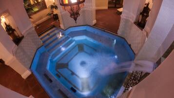 Een hottub met een geometrisch ontwerp, omgeven door stenen muren en een houten vloer.