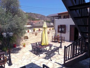 An outdoor patio area with stone flooring, outdoor furniture, and potted plants.