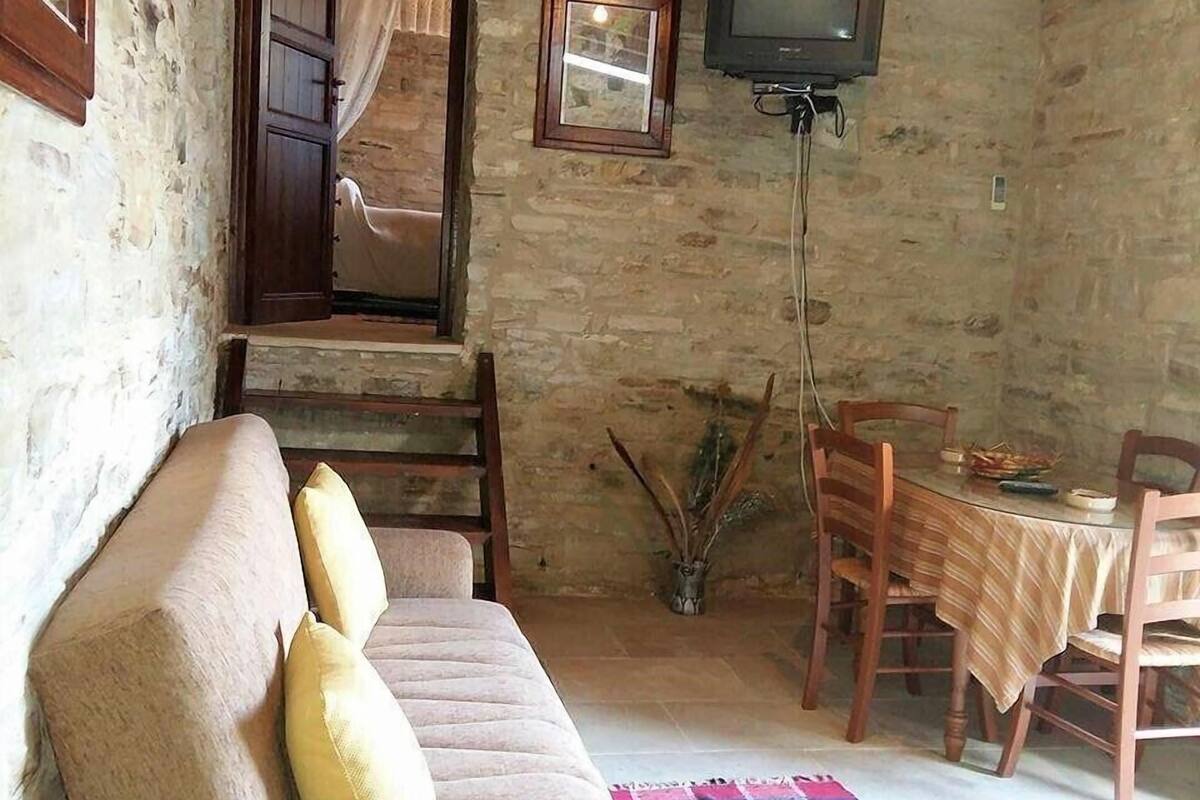 Ein gemütliches Zimmer mit einer Couch, einem Fernseher, einem Esstisch mit Stühlen und einer Treppe.