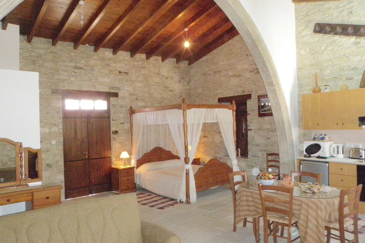 Ein Schlafzimmer mit einem Himmelbett, einer Steinwand und einer Holzbalkendecke.