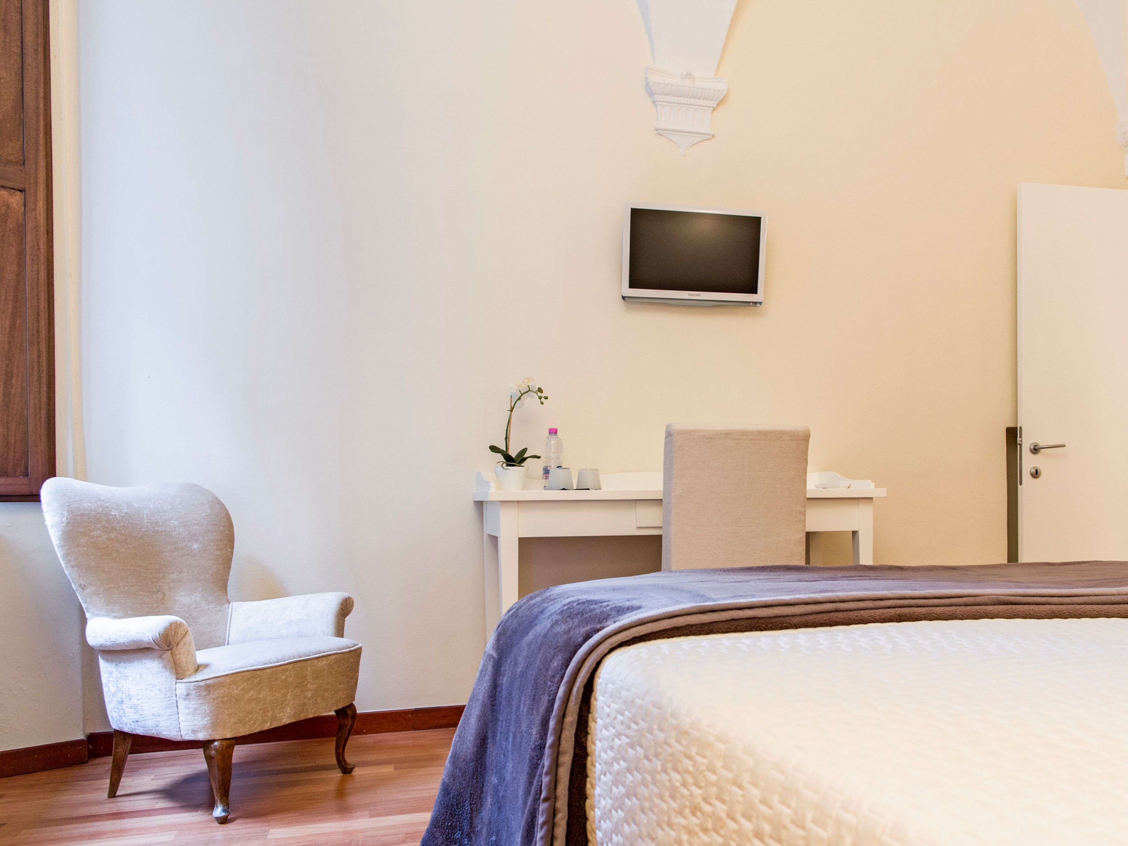 Une chambre d’hôtel avec un lit, une chaise, un bureau, une télévision et une porte.