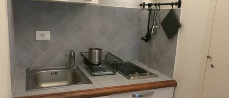 A compact kitchen with a sink, stove, and cabinets.