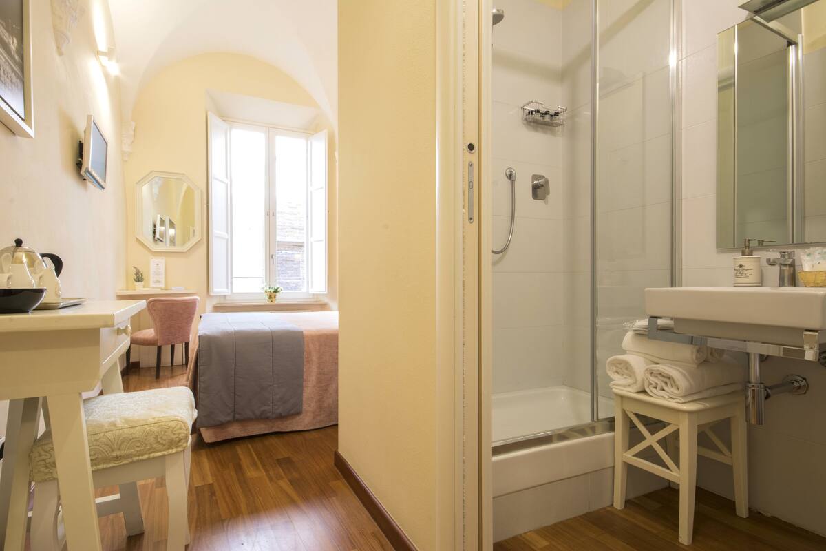 A bathroom with a shower, a sink, a mirror, and a window.
