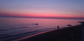 En la playa, sillas reclinables de playa, sombrillas, toallas de playa