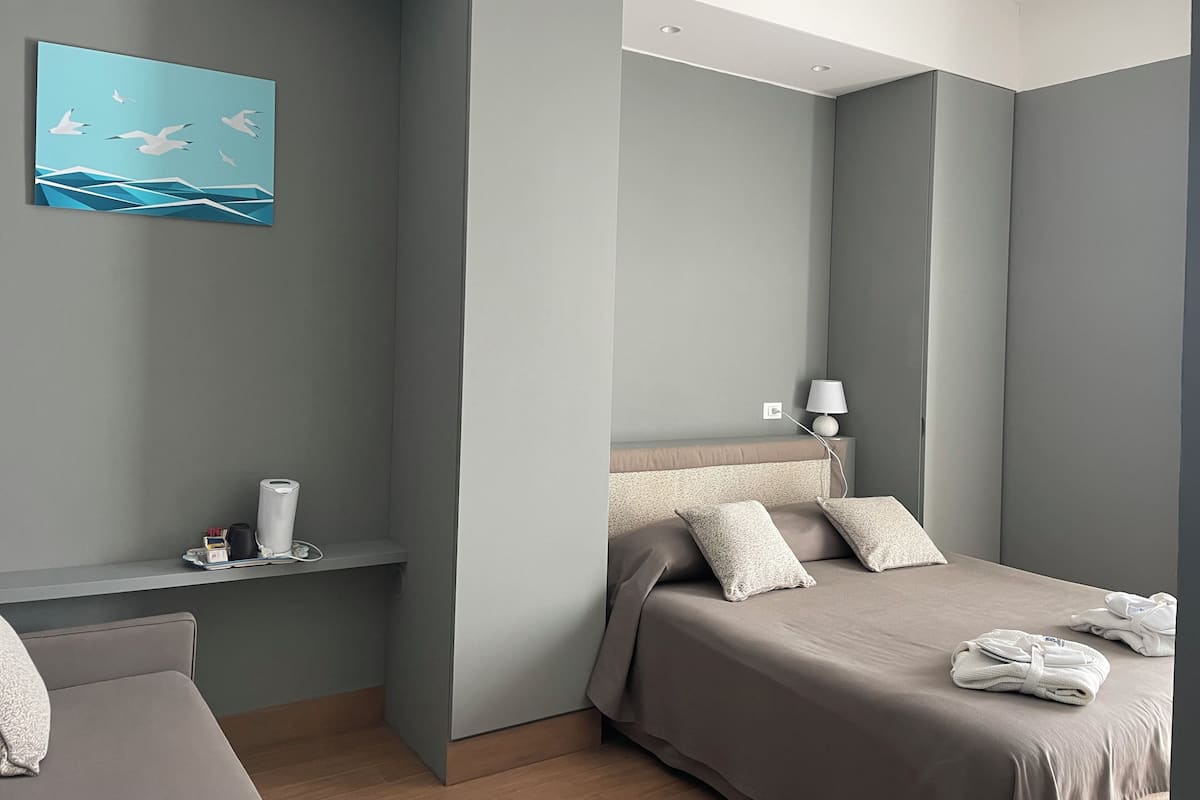 Ein modernes Hotelzimmer mit Bett, Nachttisch, Lampe und einem Bild an der Wand.