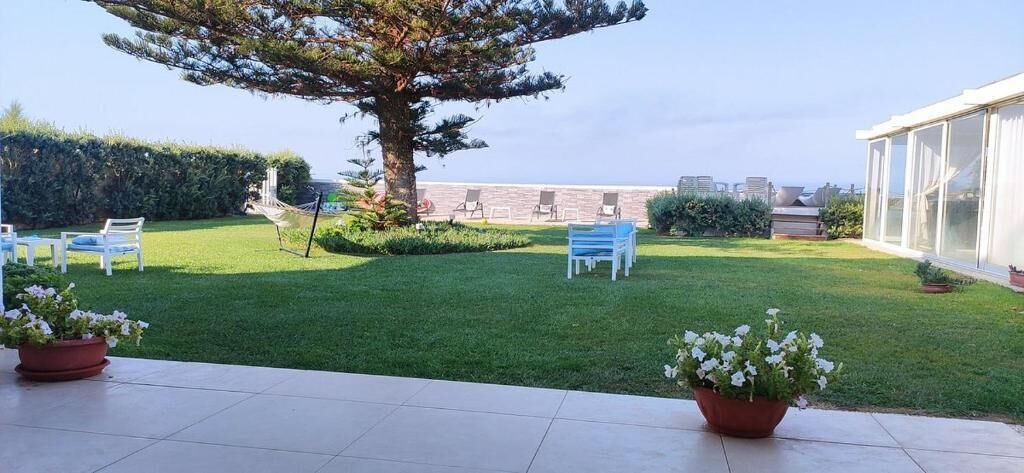 A well-maintained outdoor area with a lawn, seating arrangements, and a large tree.