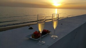 Two glasses of champagne on a table with a sunset view over the ocean.