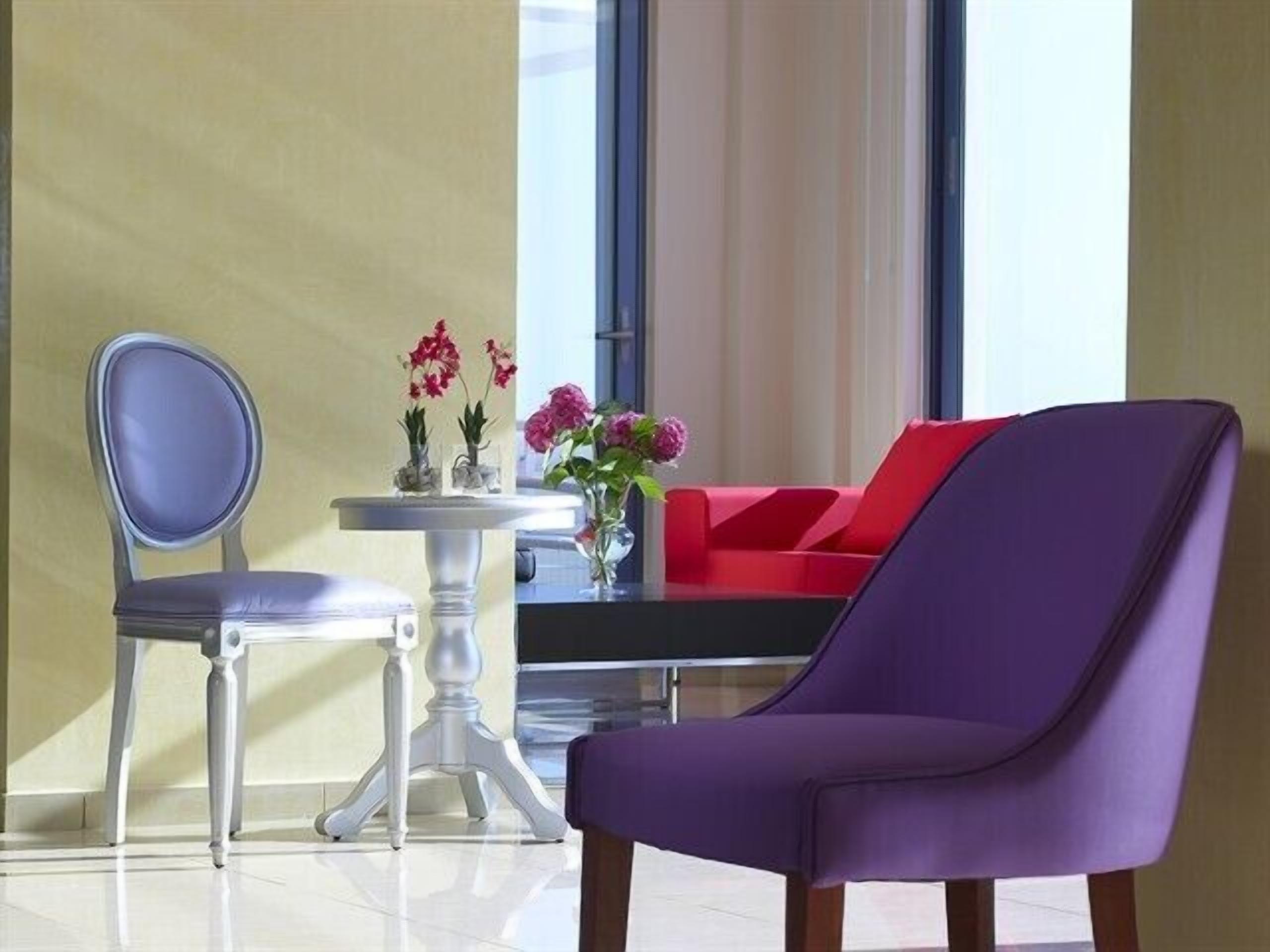 A modern room with a purple chair, a red sofa, and a small table with flowers.