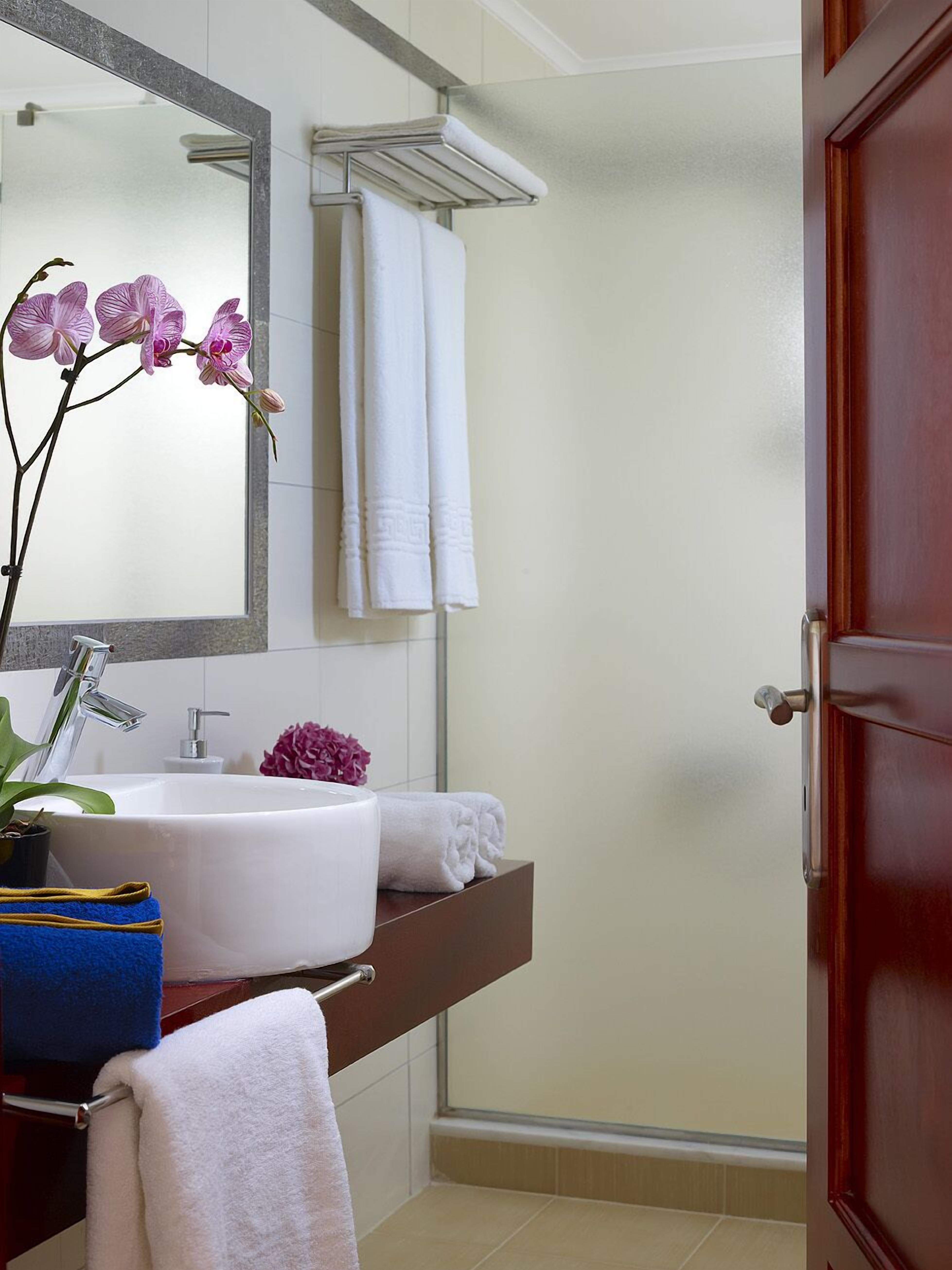 A bathroom with a white sink, a mirror, a towel rack, and a door.