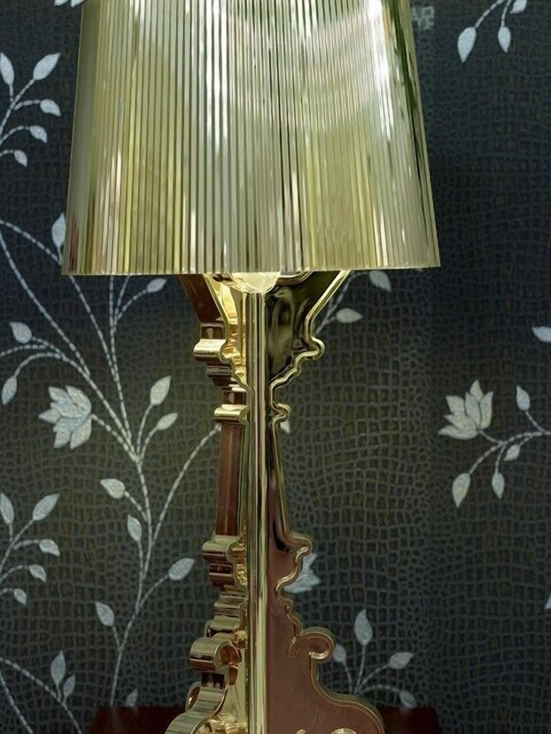 A brass table lamp with a pleated shade and an ornate base.