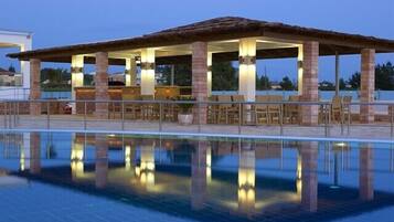 A poolside area with a covered seating area and lounge chairs.