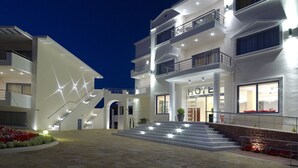 Un hotel moderno con una escalera central, varios balcones y una entrada bien iluminada.