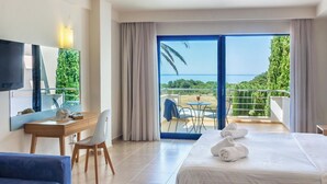 Habitación de hotel con cama, escritorio, silla, televisión y balcón con vista al mar.