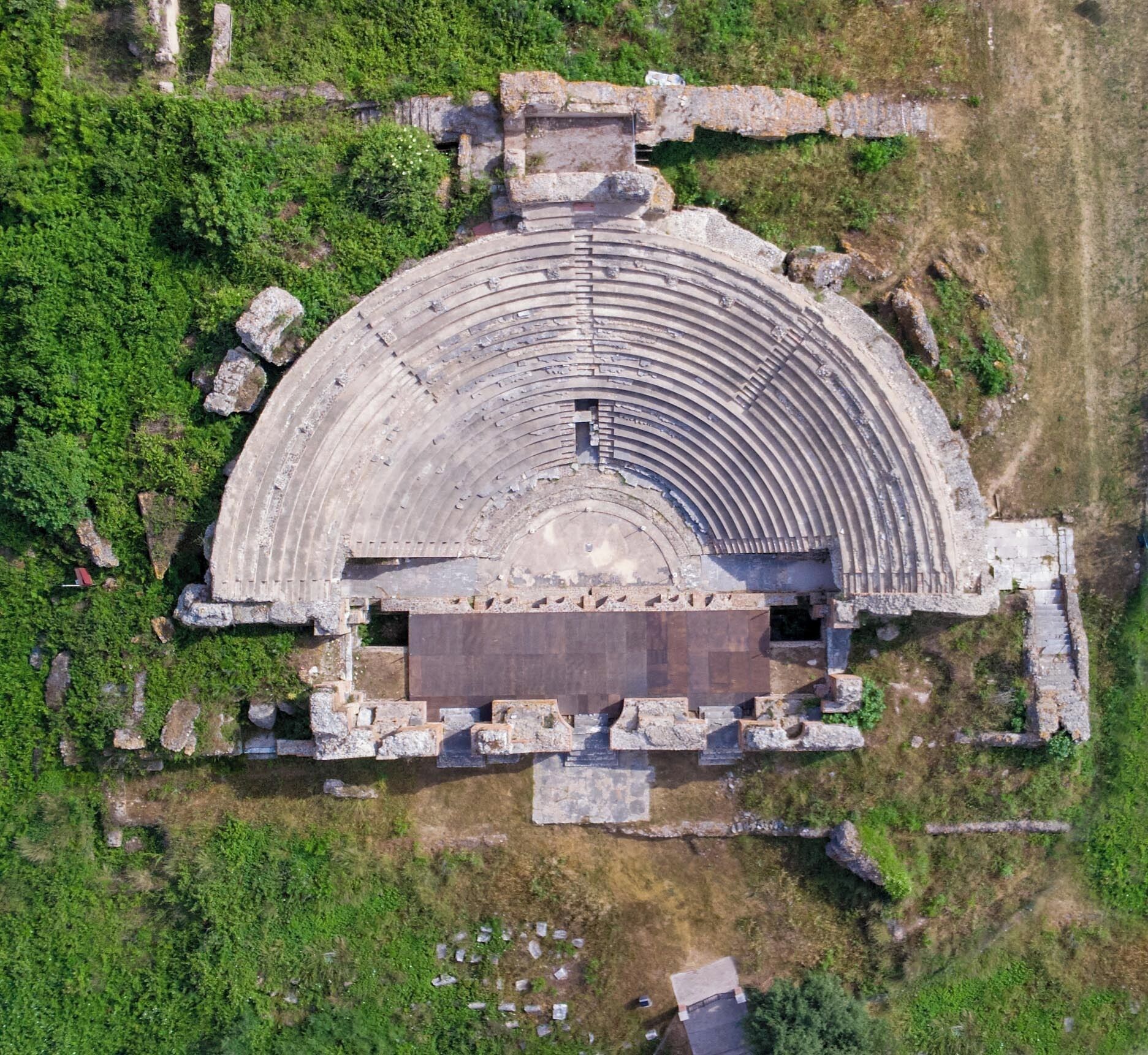 An ancient amphitheater with tiered seating and a central stage area.