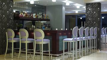 A bar area with a long counter, multiple bar stools, and a well-stocked bar.