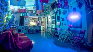 A room with a sofa, chairs, a table, and various flags and decorations. - Posada Nativa Lizard House (San Andrés)