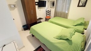 A room with two beds, a wardrobe, a desk with a chair, a television, and a mirror. - Posada Nativa Lizard House (San Andrés)