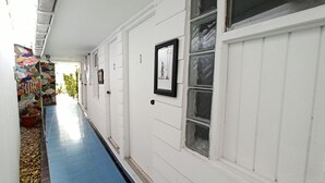 A corridor with white walls, numbered doors, and a blue floor. - Posada Nativa Lizard House (San Andrés)