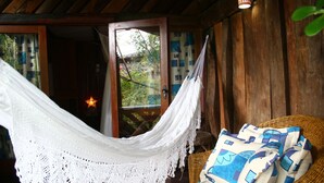 Una hamaca suspendida sobre una silla de mimbre con cojines estampados, una puerta de madera y una lámpara con forma de estrella.
