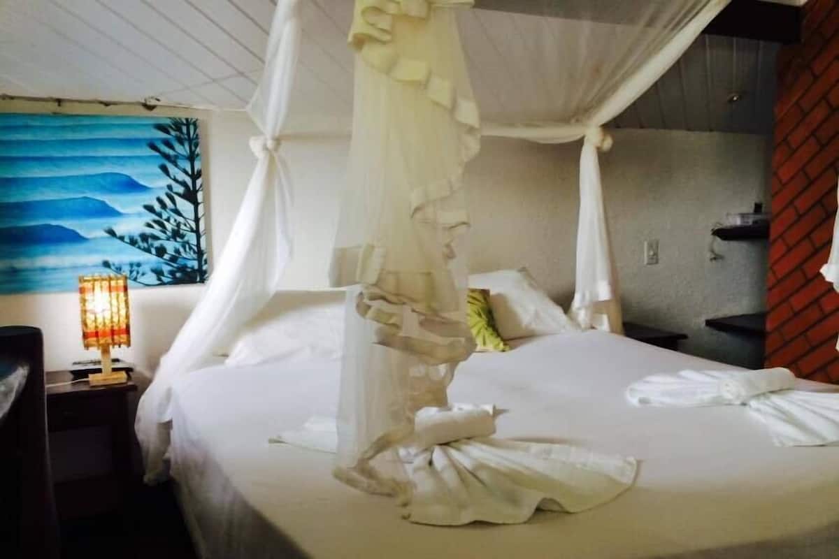 Una habitación de hotel con una cama, una mesita de noche, una lámpara y un cuadro en la pared.
