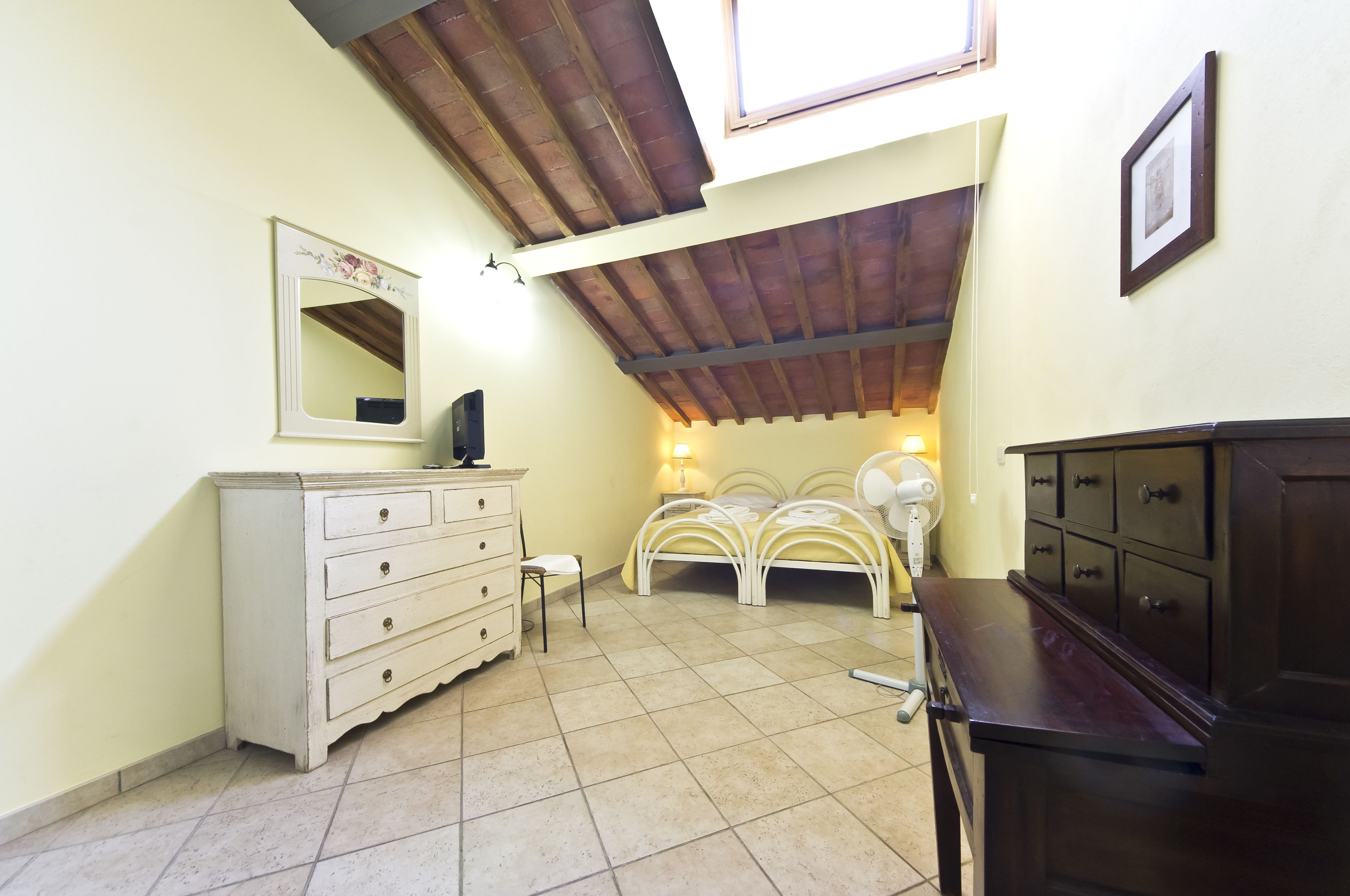 A bedroom with a bed, dresser, and a mirror on the wall.