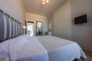 Ein Schlafzimmer mit einem großen Bett, einem an der Wand befestigten Fernseher und einem Kleiderschrank.