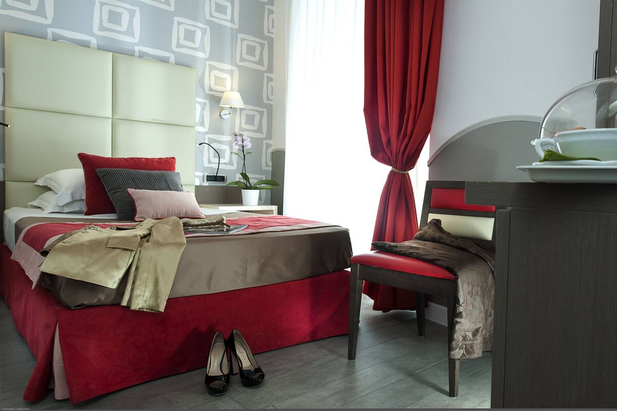 A neatly arranged bedroom with a bed, bedside table, lamp, and a chair.