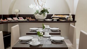 Un comedor con una mesa puesta, platos blancos, tazas y un centro de mesa decorativo con una orquídea blanca.