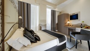 Una habitación de hotel moderna con una cama grande, un escritorio y un televisor.