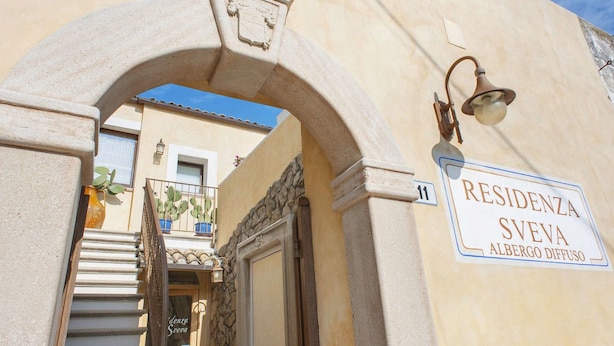 A building entrance with a stone archway, a sign reading "RESIDENZA SVEVA ALBERGO DIFFUSO", and a bell above the door. - Residenza Sveva (Bari)
