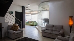Ein modernes Wohnzimmer mit zwei Sofas, einer Treppe und Blick ins Freie.