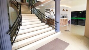 A staircase with a handrail, leading to a reception area with a counter and pendant lighting. - CLH Suites Bonito Sul - Hostel (Bonito)