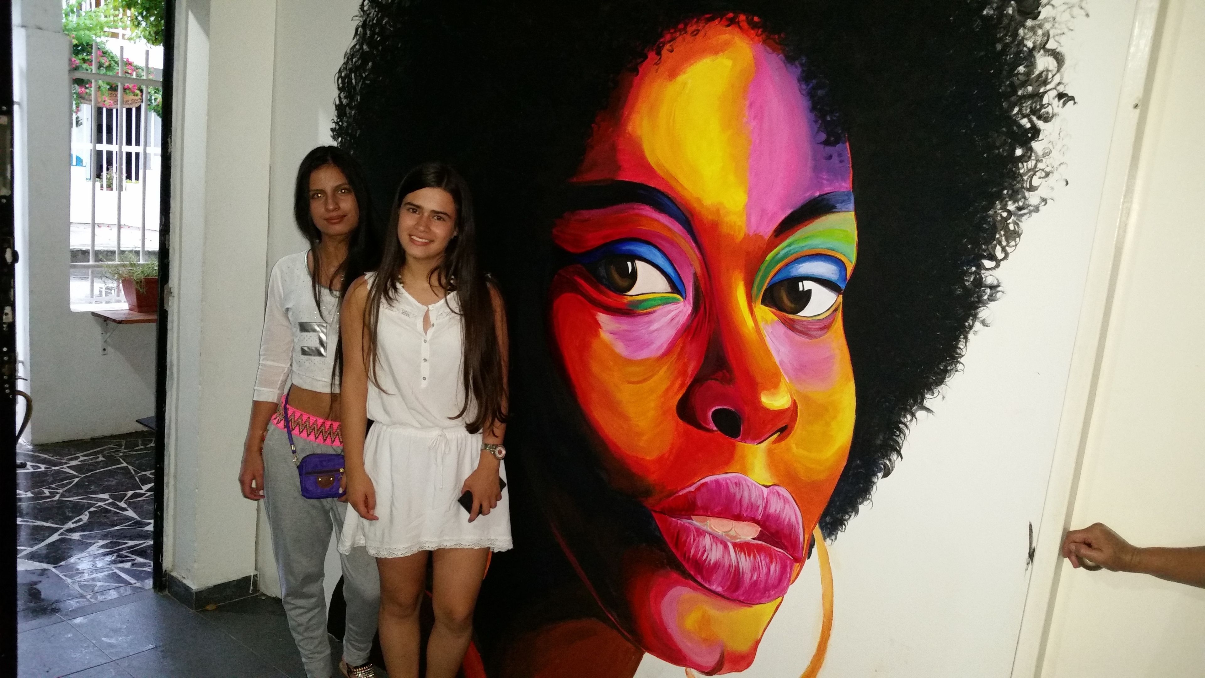 A hallway with a large mural of a colorful face on the wall.